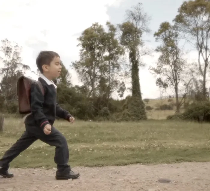 El niño sale del aula caminando con su maleta escolar