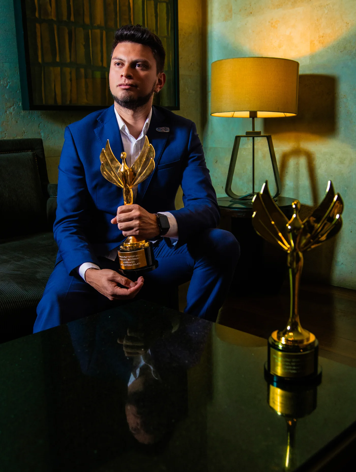 Sebastián Díaz en traje azul con sus dos trofeos de los Napolitan Victory Awards
